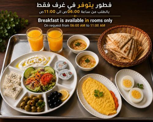 a tray of breakfast foods on a tray with orange juice at Lahdat Hotel - Al Balad in Jeddah