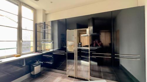 a kitchen with black walls and a stainless steel refrigerator at hotel de Croix in Morlaix