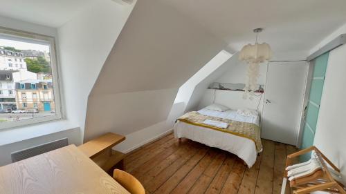 a white bedroom with a bed and a window at hotel de Croix in Morlaix