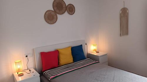 a bedroom with a bed with colorful pillows and two lamps at Casa María in Mojácar