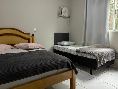 a bedroom with two beds and a window at Aluguel casa Bombinhas in Bombinhas