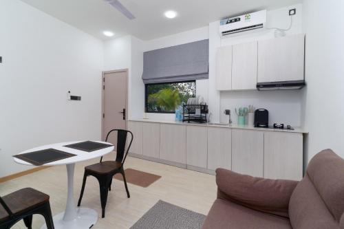 a kitchen with white cabinets and a table and chairs at Nest and nook in Ukulhas