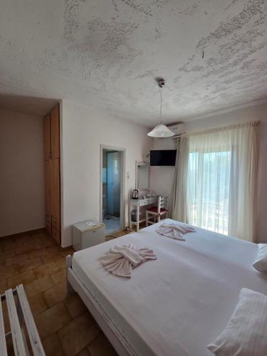 a bedroom with a large white bed and a desk at Paradise Matala Hotel in Matala
