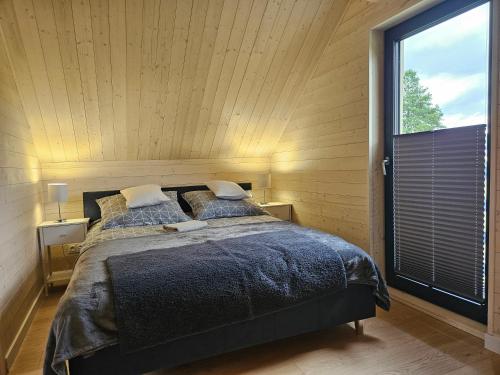 a bedroom with a bed and a large window at Domki Łomnicka Ostoja in Łomnica