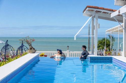 two people sitting in a swimming pool overlooking the ocean at SERHS Beach Hotel in Natal