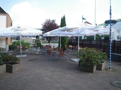 a patio with tables and chairs with umbrellas at Hotel Stadt Baunatal in Baunatal