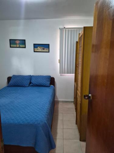 a bedroom with a bed with blue sheets and a window at relax en tucacas in Boca de Aroa