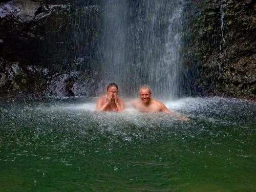 two people in the water in front of a waterfall at Pension Les Trois Cascades in Uturoa