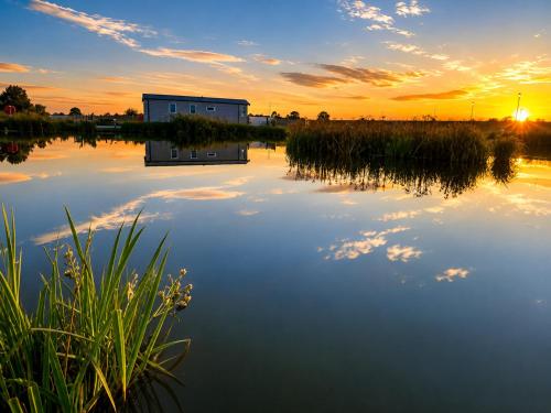 a house on the water with the sunset in the background at Parkside Fishery in Skegness