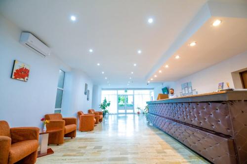 a waiting room with orange chairs and a bar at Hotel Semiramis in Saturn