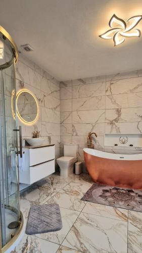 a bathroom with a tub and a toilet and a sink at Coastal Harmony B&B in Portstewart