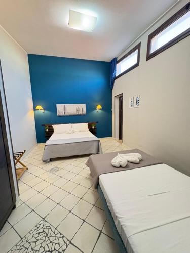 two beds in a room with a blue wall at Sun Tower beach apartments in Mazara del Vallo