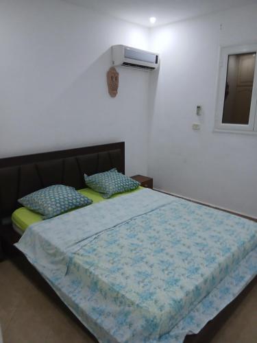 a bedroom with a bed with a blue comforter and a window at Ridha in Djerba