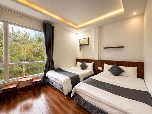 a hotel room with two beds and a window at CaRa Hotel Đà Lạt in Da Lat