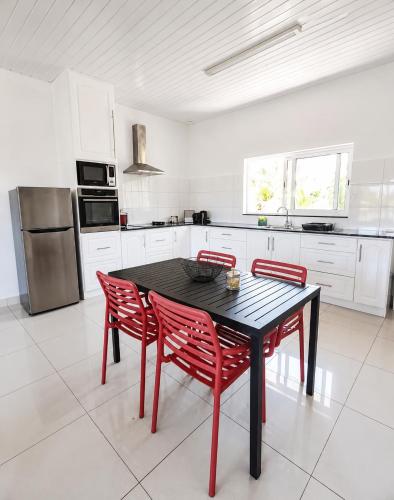 a kitchen with a black table and red chairs at Trwa Koko Self-catering in Grand'Anse Praslin