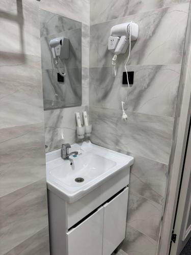 a white bathroom with a sink and a mirror at shahrisabz city hotel in Shahrisabz