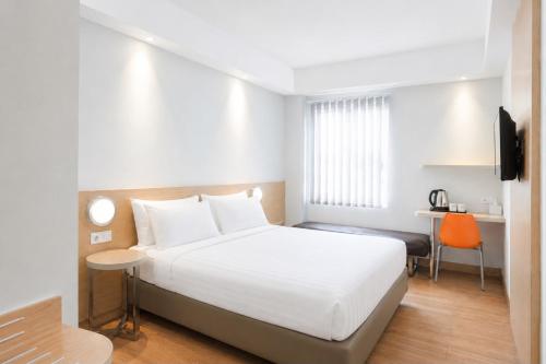 a bedroom with a white bed and a desk at Indies Style Malioboro Hotel in Yogyakarta