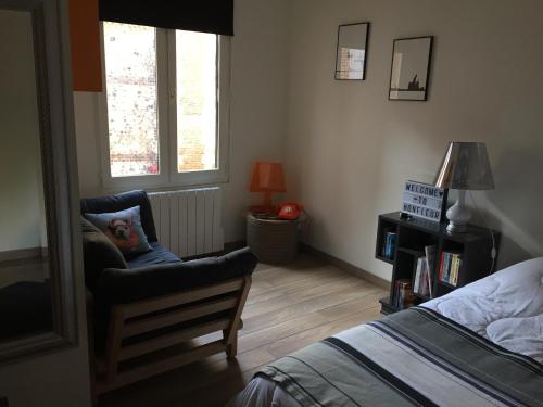 - une chambre avec une chaise, un lit et une fenêtre dans l'établissement L appart de la place Ste Catherine, à Honfleur