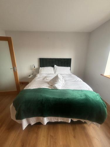 a bedroom with a large green blanket on a bed at Ballyconneely house in Ballyconneely