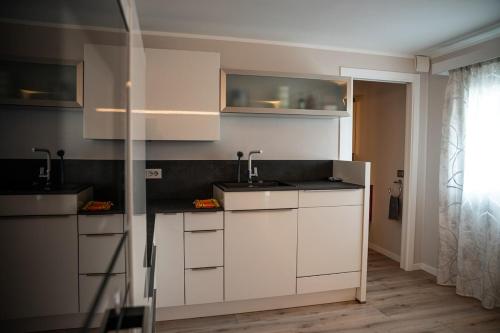 a kitchen with white cabinets and sinks and a window at Entire house for couple with exclusive pool in Monsanto