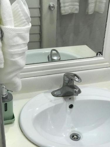 a bathroom sink with a faucet in front of a mirror at Carib Ochi Rios condominium in Ocho Rios