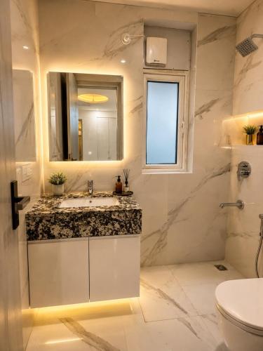 a white bathroom with a sink and a mirror at Gurgaon Legacy in Gurgaon