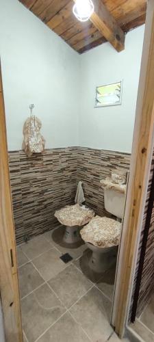 a bathroom with two toilets and a brick wall at Cálida Casa con amplio espacio verde en Raco in Raco
