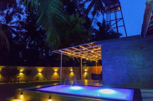 a swimming pool with lights in a backyard at night at Midtown Mansion in Veyangoda