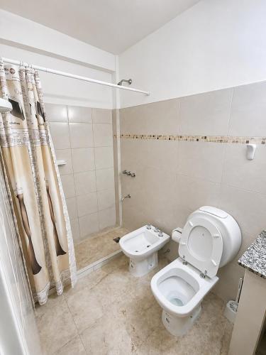 a white bathroom with a toilet and a sink at Center Studio 3pax apartamento in Trelew