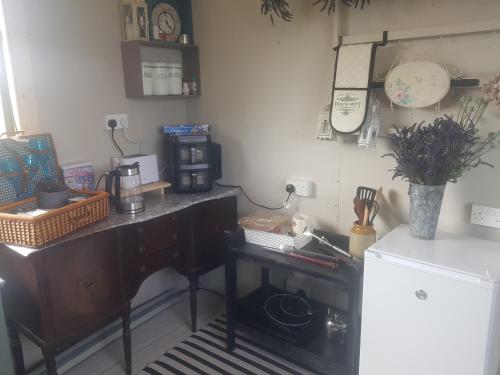 a kitchen with a desk with a coffee maker and a refrigerator at Tiny living on the Wild Atlantic Way in Tralee