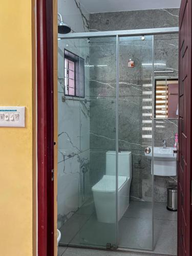 a bathroom with a glass shower and a toilet at Kattuvallil AGAPE Homestay 4B2HK in Thiruvalla