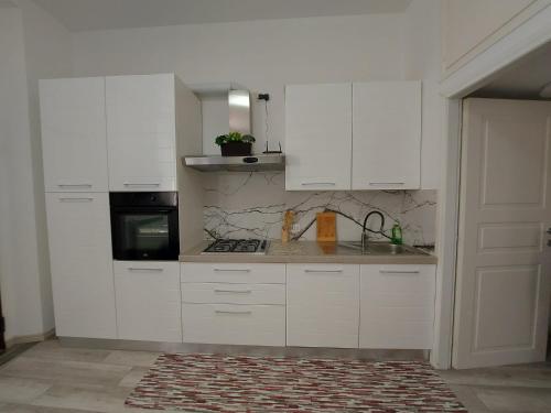 a white kitchen with white cabinets and a stove at Appartamento viktor in Cislago