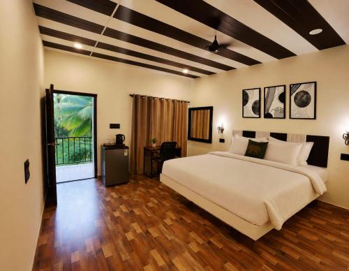 a bedroom with a large white bed and wooden floors at Coco Nest Mandrem in Mandrem