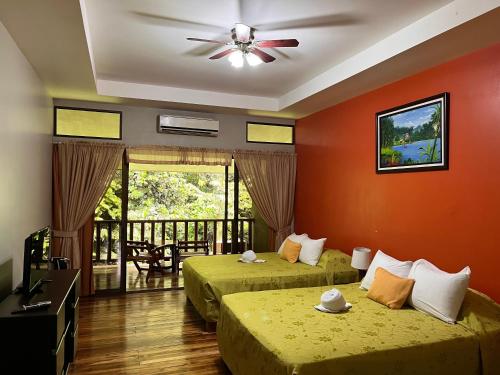a hotel room with two beds and a ceiling fan at Hotel El Bambu in Sarapiquí