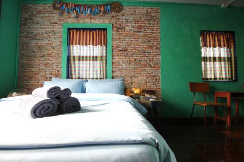 a green bedroom with a bed with towels on it at Baan Nai Nakhon in Songkhla