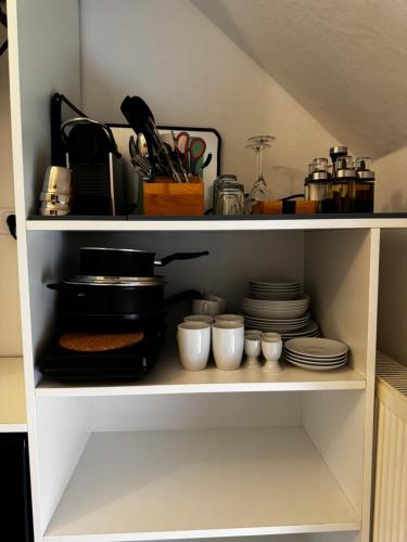 a shelf with plates and cups and utensils at Jade Villa an der Nordsee in Jaderaltendeich