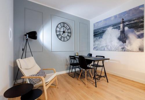 a dining room with a table and chairs and a clock at Lighthouse Apartment Nadmorze - 150 m od morza, ogródek, garaż in Gdańsk