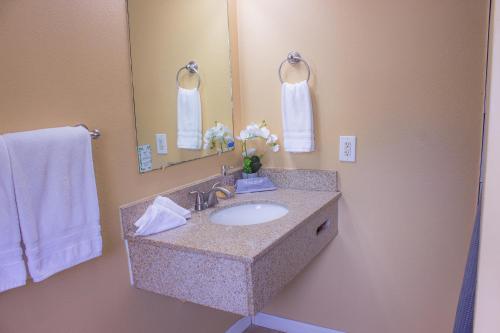 a bathroom with a sink and a mirror and towels at Carmel Wayfarer Inn in Carmel