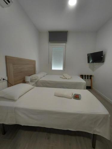 a bedroom with two beds and a television and a window at Corvera Guss in Corvera