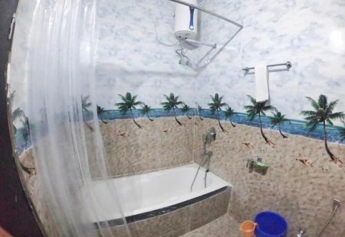 a bathroom with a tub and a shower with palm trees at Hotel A3cube in Panna