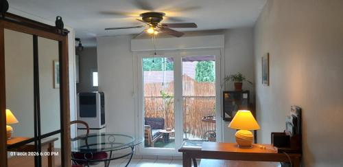 a living room with a table and a ceiling fan at Suite-Appart Beau Soleil - 24H Le Mans Métropole in Allonnes