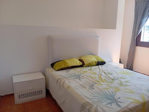 a bedroom with a bed with two yellow pillows at Villa pieds dans l'eau Cabo in Cabo Negro