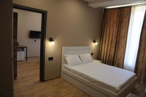 a bedroom with a white bed and a mirror at Mn Hotel Borjomi in Borjomi
