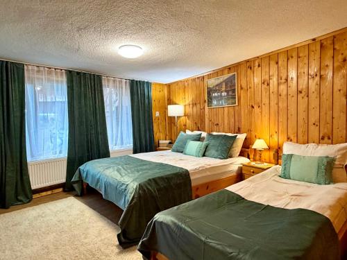 a hotel room with two beds and wooden walls at Златкова къща in Koprivshtitsa