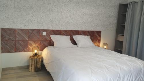 a bedroom with a white bed with two candles at Gîte La Ferme Ecole in Perrou