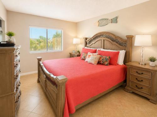 a bedroom with a bed with red sheets and a window at Beach Palms- Unit 102 in Clearwater Beach