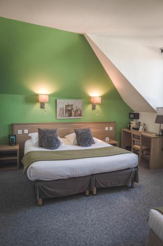a bedroom with a large bed with a green wall at Hôtel Le Rohan Charme et Caractère in Pontivy