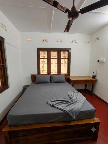 a bed in a room with a ceiling fan at Amma's Homestay in Jaffna