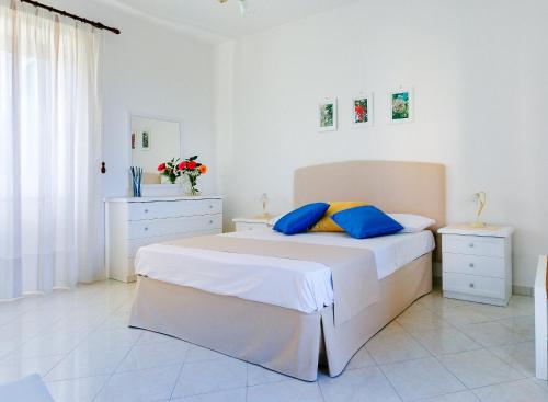 a white bedroom with a large bed with blue pillows at Casa al Belvedere in Vico Equense