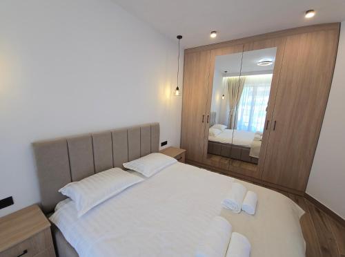 a bedroom with a large white bed with a mirror at Apartamente Nefeli in Curtea de Argeş